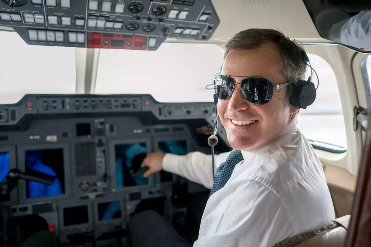 Pilot handing over documents to a new owner in front of a jet.